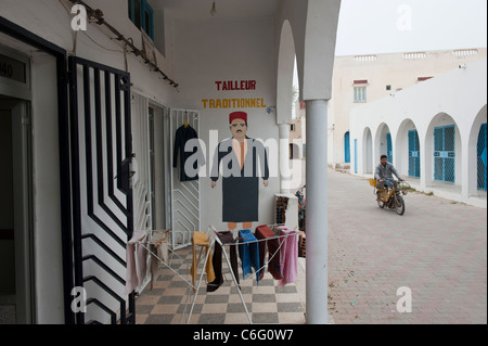 A Tunisian on a small motorbike passes a traditional tailors shop. Guellala. Djerba. Tunisia. North Africa Stock Photo