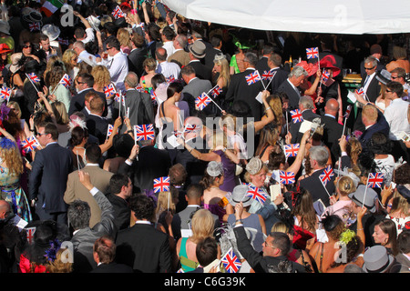 Crowds waving Union Jack flags amass around the bandstand for the end of evening signalong Ladies' Day at Royal Ascot Stock Photo