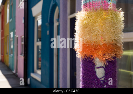 knitted sleeve around a lamppost in front of multi coloured terrace of houses southsea england uk Stock Photo
