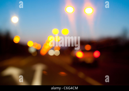 Street lights and car tail lights on a road at dusk Stock Photo