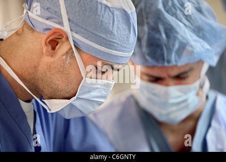 A doctor and nurse work on a patient in an operating room. Stock Photo