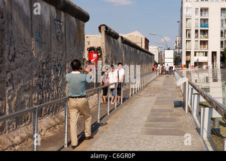 Tourists taking a photograph at a Berlin Wall remnant on Niederkirchnerstrasse. Stock Photo