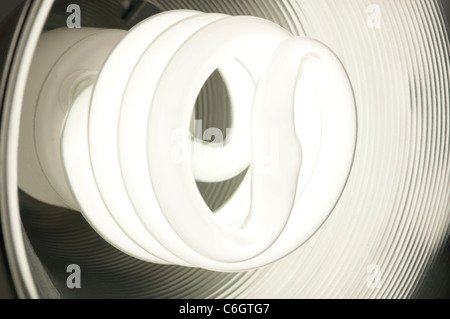 Energy saving compact fluorescent bulb glowing inside a round metal dish Stock Photo