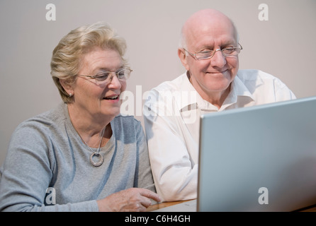 Mature couple smiling and enjoying using a laptop computer Stock Photo