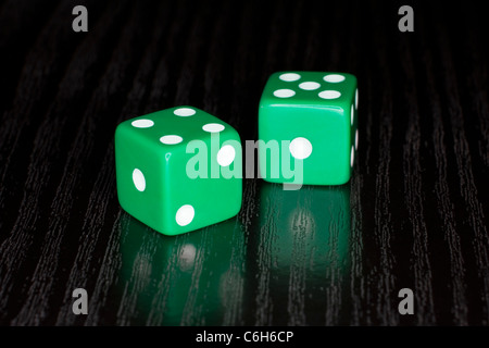 Green Dice on a semi reflective black surface Stock Photo