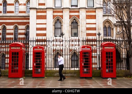 Mobile phone user next to red phone boxes near the High Court, Chancery Lane, London Stock Photo