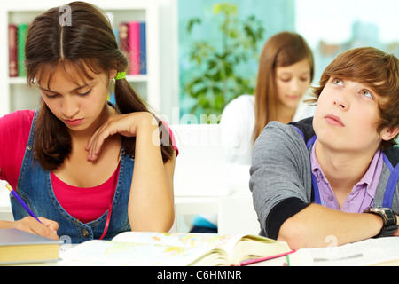 Portrait of smart guy thinking with his classmates near by making notes in copybook Stock Photo