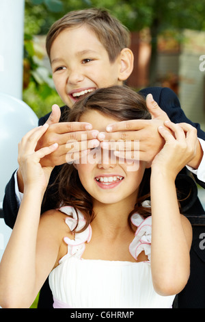Portrait of laughing boy groom shutting eyes of his cheerful bride Stock Photo