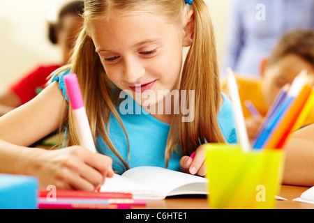 Portrait of lovely girl drawing in copybook at lesson Stock Photo