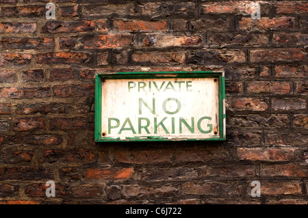 Old fashioned no parking sign with crumbling pain on a red brick wall Stock Photo