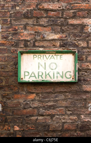 Old fashioned no parking sign with crumbling pain on a red brick wall Stock Photo