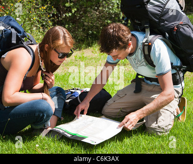 A young couple backpacking, backpackers, reading, studying a map. Northland, North Island, New Zealand Stock Photo