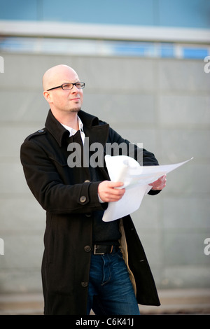 Architect with helmet under the arm and a construction plan in his hands Stock Photo