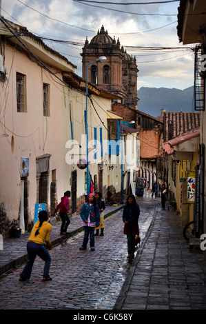 Children playing volleyball on a wet street, Cuzco, Peru Stock Photo