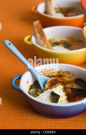 Oeufs en cocotte with herbs and spices, served in individual ramekins Stock Photo