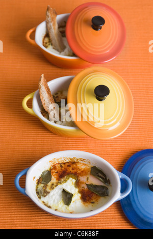 Oeufs en cocotte with herbs and spices, served in individual ramekins Stock Photo