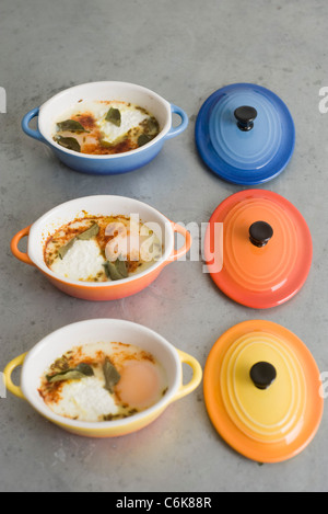 Oeufs en cocotte with herbs and spices, served in individual ramekins Stock Photo