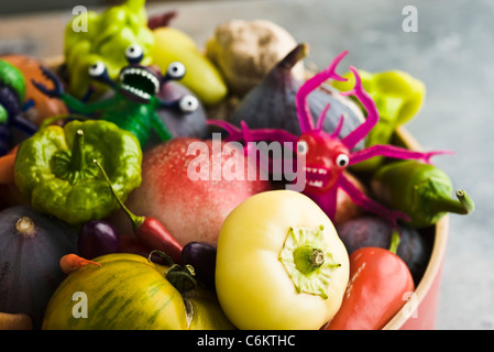 Fresh vegetables and fruit in bowl with plastic monster toys Stock Photo