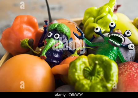 Fresh vegetables and fruit in bowl with plastic monster toys Stock Photo