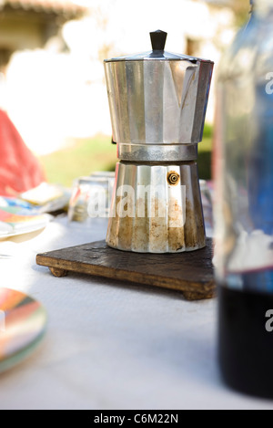 Espresso maker resting on trivet on outdoor table Stock Photo