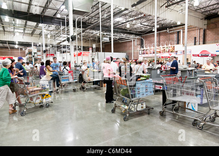 customers step briskly up to checkout lines with loaded shopping carts in Costco USA big box retailer market Stock Photo