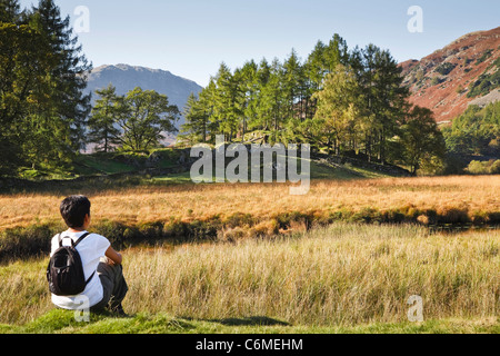 A young Indian Asian woman rests on a hike in the English countryside