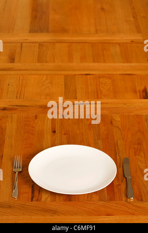 Wooden table with a single plate and cutlery. Lots of space for copy. Stock Photo