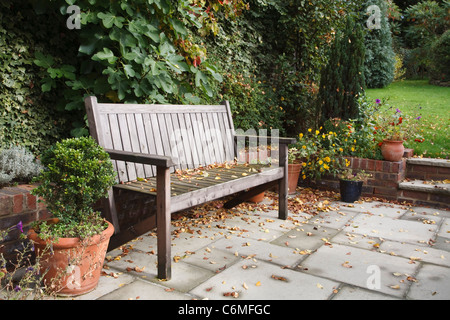 Garden bench on a traditional flagstone patio in autumn / fall Stock Photo