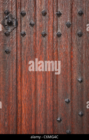 Detail of an ancient medieval wooden door with decorated wrought iron studs Stock Photo