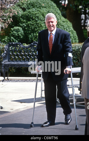 President Bill Clinton walks with crutches as he recovers from a knee injury at the White House April 3, 1997. Stock Photo