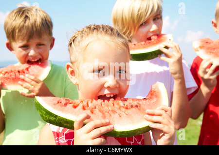 Children eating red watermelon on blue sky background Stock Photo