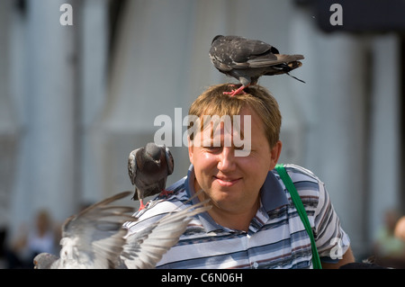 A tourist feeding the pigeons in Piazza San Marco (known in English as St. Marks Square) in the centre of Venice, Italy. Stock Photo