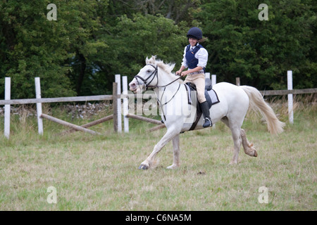 Smiling teenage rider cantering on white horse North Cotswold Pony Club Camp 2011 Cotswolds UK Stock Photo