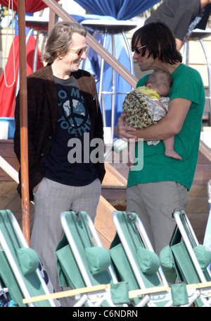 Jim Carrey holding his grandson Jackson Santana while talking to Gary Oldman on Malibu Beach Malibu, California - 04.07.10 Stock Photo