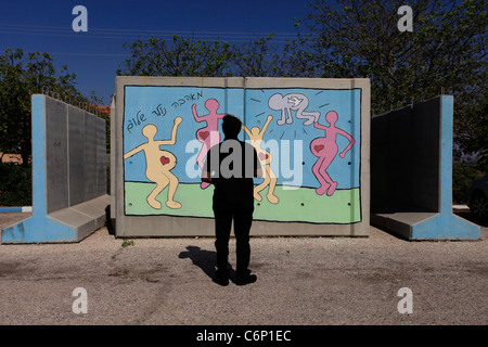 An Israeli man stands in front of steel-reinforced precast concrete blast wall placed around a freestanding bomb shelter called Migunit in Hebrew in Kibbutz Netiv Ha'asara near the Gaza border Southern Israel Stock Photo