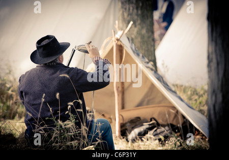 A soldier in a Civil War reenactment reloads his rifle with gun powder Stock Photo