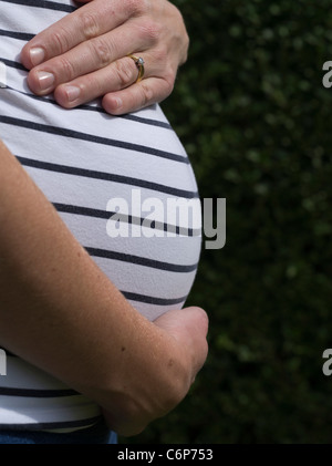 dh Mothers Pregnancy Stomach FAMILY UK Pregnant tummy woman bump mother adult profile belly from side view hand Stock Photo