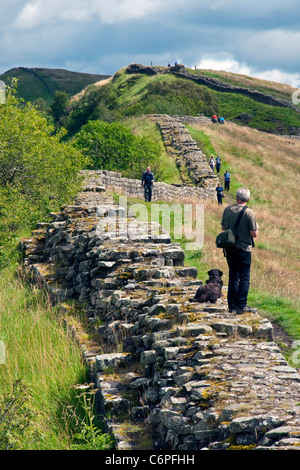 Dramatic Whin Sill Crag section of Hadrian's Wall at Cawfields in Northumberland National Park, with hikers on National Walking Stock Photo