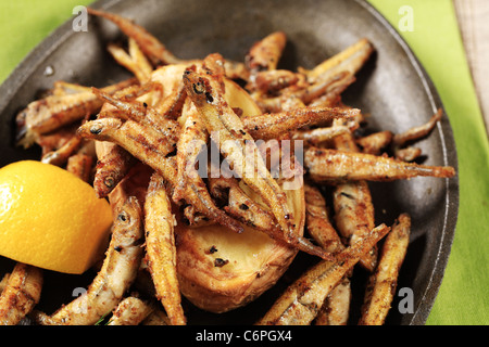 Fried anchovies and potato on cast iron pan Stock Photo