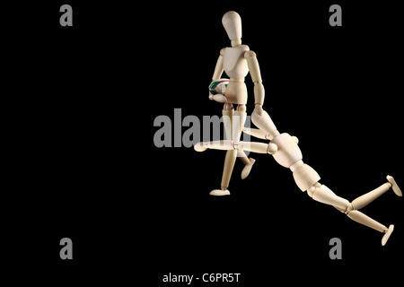 Wooden Mannequin shown with rugby ball isolated on black Stock Photo