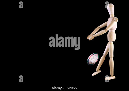 Wooden Mannequin shown with rugby ball isolated on black Stock Photo