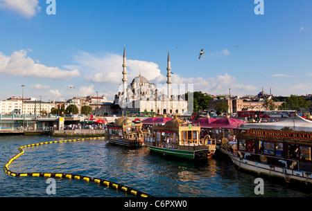 Yeni Camii Mosque (New Mosque) on the waterfront of the Golden Horn in Eminonu, with pleasure boats on the foreground.  Istanbul Stock Photo