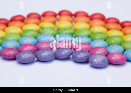 Rainbow smartie pattern on a white background. Stock Photo