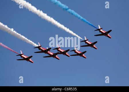 British RAF 'Red Arrows' display team, flypast of Hawk T1 jets with colourful red, white and blue [vapour trails], England, UK Stock Photo