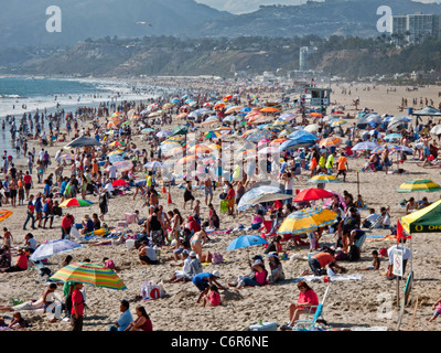 A weekend crowd enjoys Pacific Ocean summer weather on the beach in Santa Monica, CA. Stock Photo