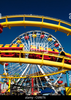 A roller coaster and a Ferris wheel are juxtaposed at the amusement park on Santa Monica Pier. Stock Photo