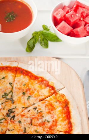 Italian original thin crust pizza Margherita with gazpacho soup and watermelon on side,and vegetables on background Stock Photo