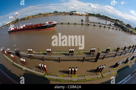 Fisheye view of a red-painted cargo ship sailing through a lock gate at the Kiel Canal Stock Photo