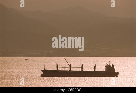 Silhouette of a distant dry bulk freighter in ballast. Stock Photo