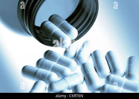 Pharmaceutical capsules or pills pouring out of bottle in blues Stock Photo